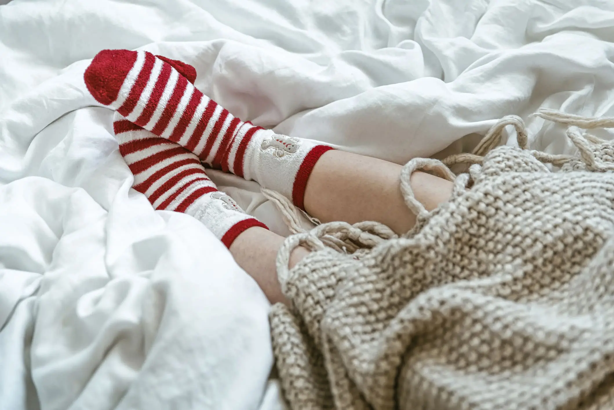 Woman wearing warm red socks in bed. Cozy winter day